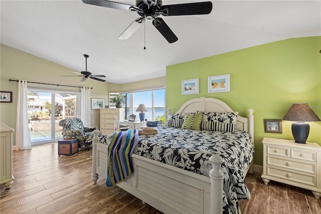 bedroom featuring lofted ceiling, access to outside, multiple windows, and wood finished floors