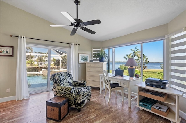 office area featuring wood finished floors, baseboards, a sunroom, vaulted ceiling, and a water view