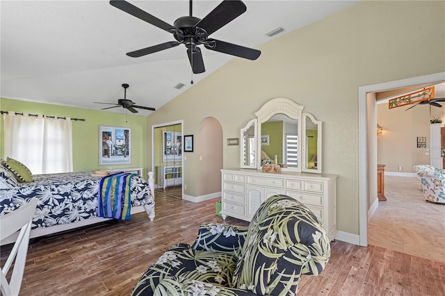 bedroom featuring wood finished floors, baseboards, visible vents, arched walkways, and vaulted ceiling