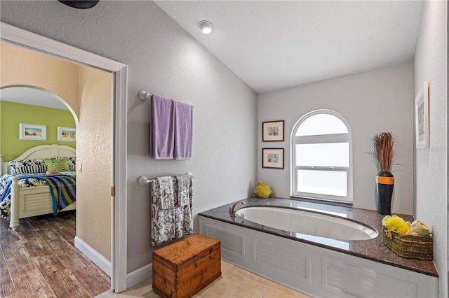 ensuite bathroom featuring baseboards, a garden tub, and ensuite bathroom