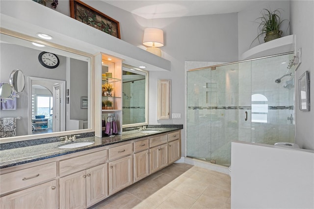 full bath featuring a sink, a stall shower, double vanity, and tile patterned flooring