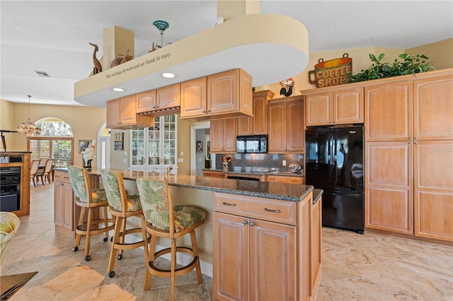 kitchen with a kitchen bar, visible vents, black appliances, dark stone countertops, and tasteful backsplash