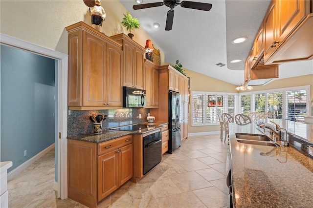 kitchen with black appliances, a sink, dark stone countertops, backsplash, and vaulted ceiling