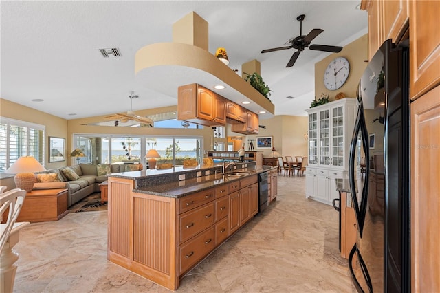 kitchen with visible vents, dark stone counters, black appliances, and lofted ceiling