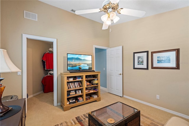 interior space with ceiling fan, light colored carpet, visible vents, and baseboards