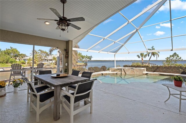 view of patio with glass enclosure, outdoor dining space, a pool with connected hot tub, ceiling fan, and a water view