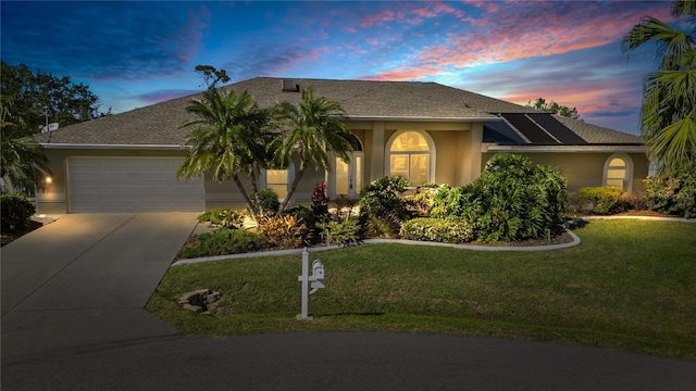 single story home featuring an attached garage, a shingled roof, stucco siding, concrete driveway, and a front lawn