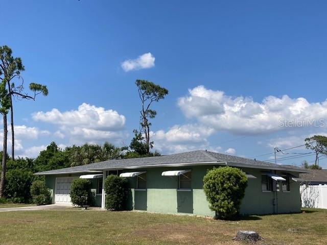 exterior space with concrete driveway, a yard, an attached garage, and fence