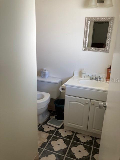 half bath featuring tile patterned flooring, vanity, and toilet