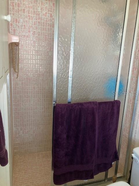 full bath with tiled shower and toilet