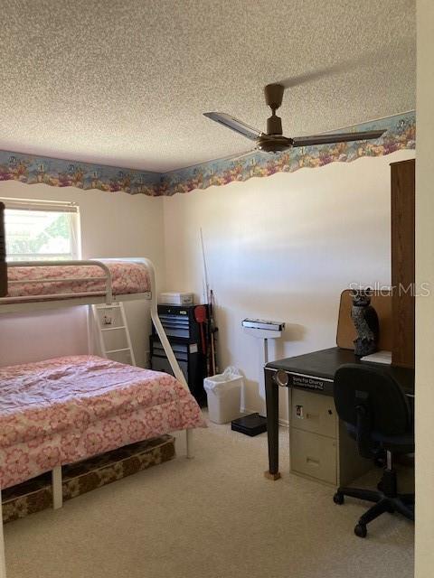 bedroom featuring a textured ceiling, carpet floors, and a ceiling fan