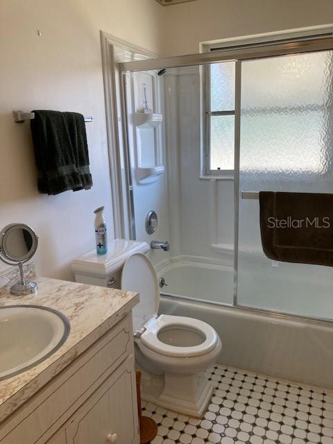 bathroom with shower / bath combination with glass door, vanity, and toilet