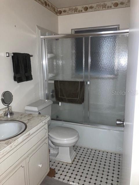 bathroom featuring enclosed tub / shower combo, vanity, and toilet