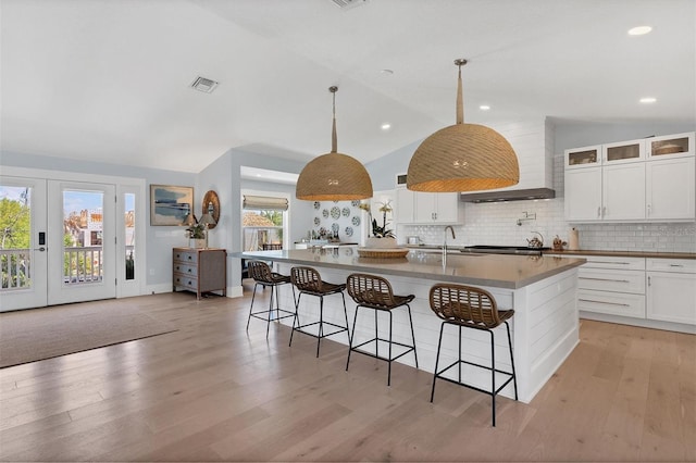 kitchen featuring light wood-type flooring, visible vents, backsplash, and vaulted ceiling