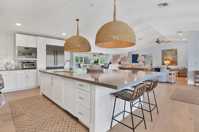 kitchen with visible vents, a sink, vaulted ceiling, appliances with stainless steel finishes, and light wood-type flooring