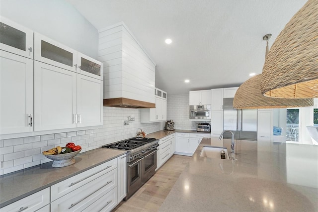 kitchen with backsplash, stainless steel appliances, glass insert cabinets, and a sink