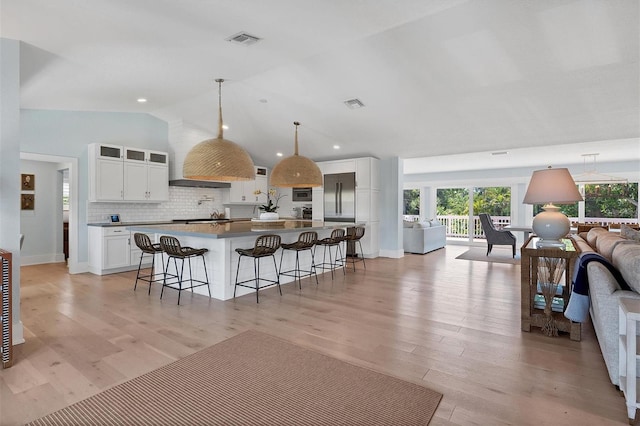 kitchen featuring visible vents, a kitchen breakfast bar, light wood-style floors, and open floor plan