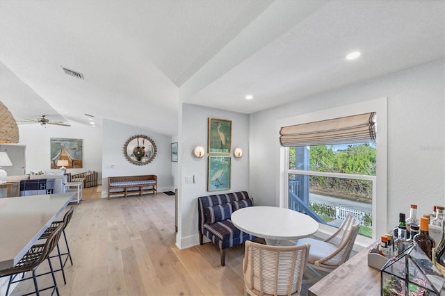 dining room with light wood-type flooring, visible vents, a ceiling fan, baseboards, and vaulted ceiling