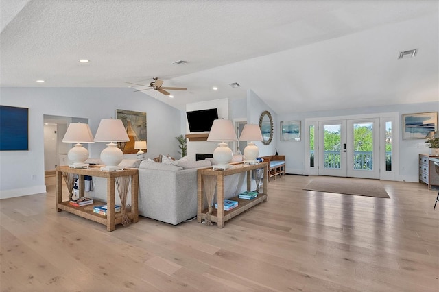 living room featuring french doors, visible vents, wood finished floors, and vaulted ceiling