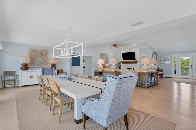 dining space with light wood finished floors, visible vents, lofted ceiling, recessed lighting, and a fireplace