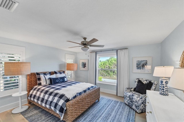 bedroom with visible vents, baseboards, a ceiling fan, and wood finished floors