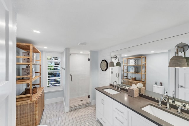 bathroom with a sink, a stall shower, double vanity, and tile patterned flooring