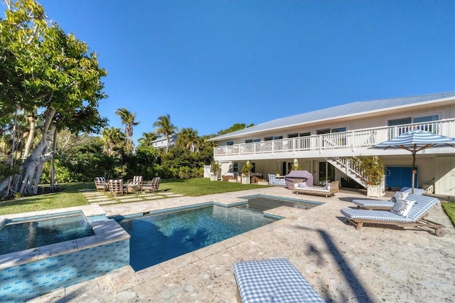 pool featuring a patio, stairway, a yard, a hot tub, and a deck