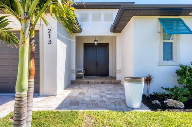 view of exterior entry featuring stucco siding and a garage