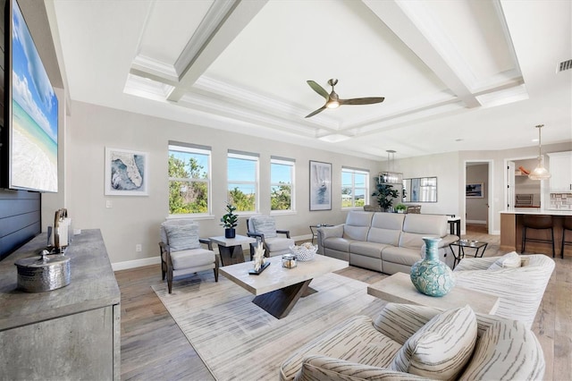 living room featuring visible vents, crown molding, baseboards, light wood-type flooring, and beam ceiling