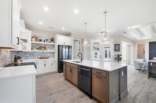 kitchen with a sink, dishwasher, light countertops, freestanding refrigerator, and open shelves