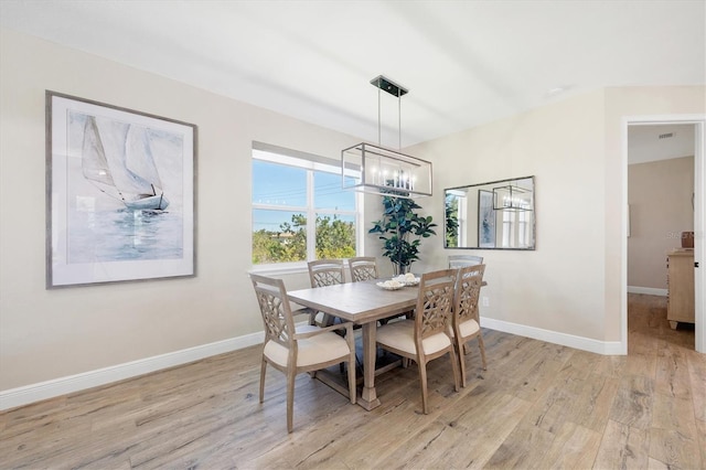 dining area featuring an inviting chandelier, baseboards, and light wood-style floors