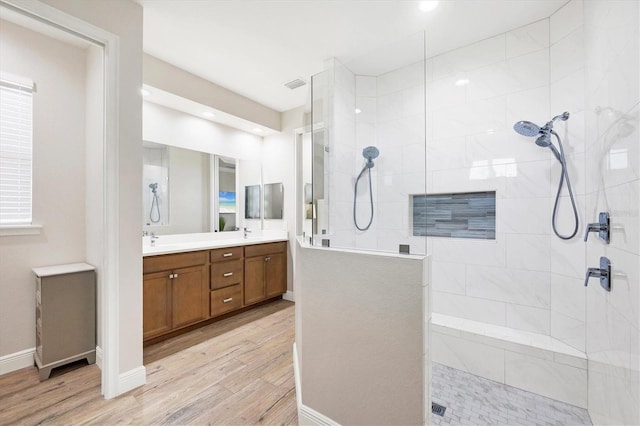 full bath featuring wood finished floors, baseboards, visible vents, double vanity, and walk in shower