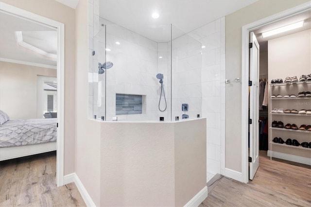 ensuite bathroom with baseboards, walk in shower, wood finished floors, and ensuite bathroom