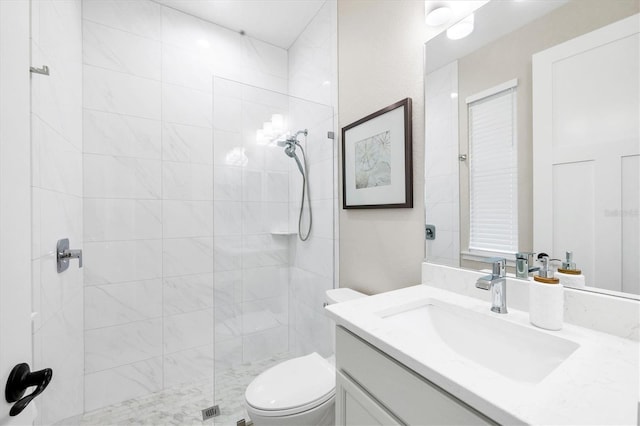 bathroom with tiled shower, toilet, and vanity