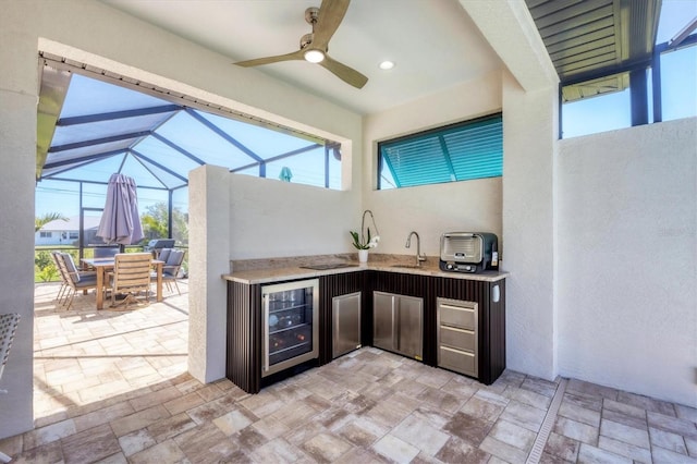 view of patio / terrace featuring wine cooler, exterior kitchen, outdoor dining space, a ceiling fan, and a sink