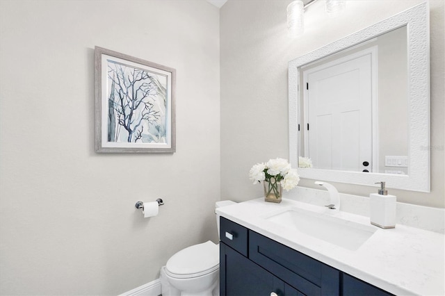 bathroom with toilet, vanity, and baseboards