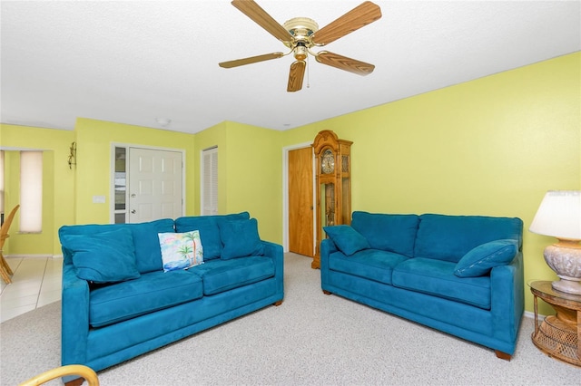 tiled living area with a textured ceiling, baseboards, and ceiling fan