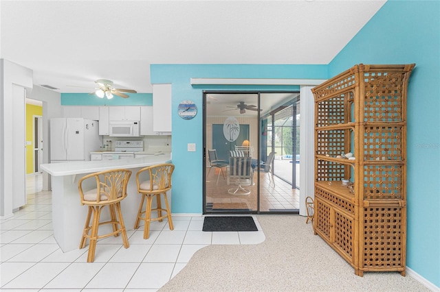 kitchen featuring white appliances, light countertops, a ceiling fan, and white cabinetry