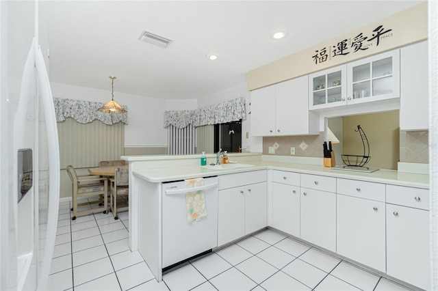 kitchen featuring visible vents, light countertops, a peninsula, white appliances, and a sink