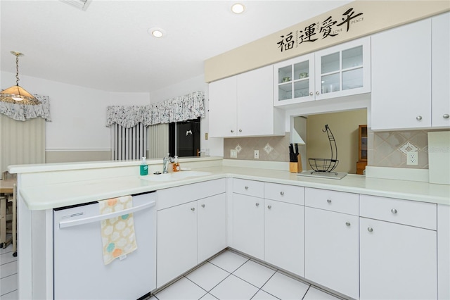 kitchen with dishwasher, light countertops, a peninsula, white cabinets, and a sink