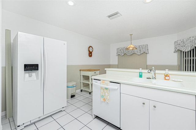 kitchen with white appliances, visible vents, a sink, light countertops, and white cabinetry