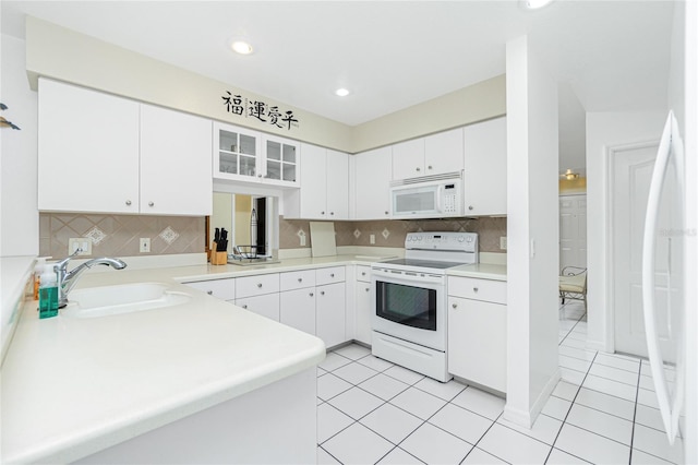 kitchen with a sink, white appliances, tasteful backsplash, and white cabinets