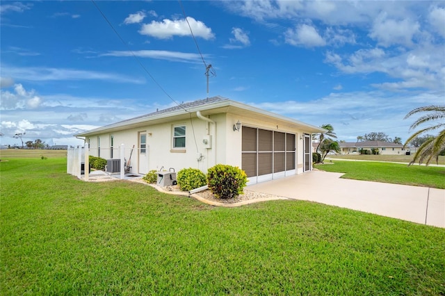 back of house featuring cooling unit, stucco siding, driveway, and a lawn