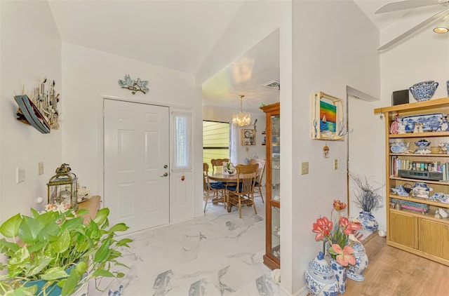 foyer entrance with visible vents, a notable chandelier, and marble finish floor