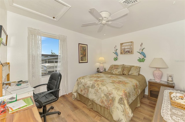 bedroom featuring a ceiling fan, attic access, light wood-style floors, and visible vents