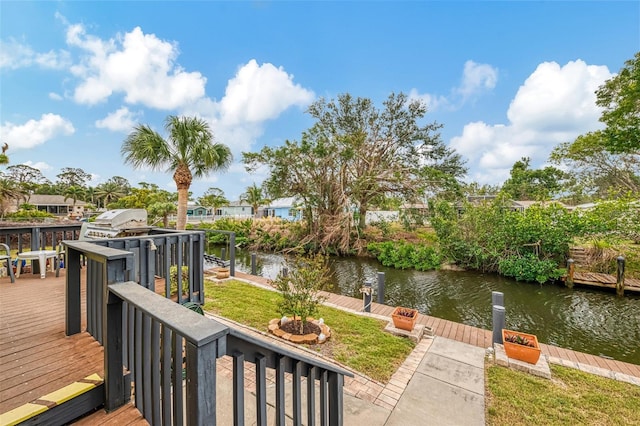 wooden deck featuring a yard, a water view, area for grilling, and a boat dock