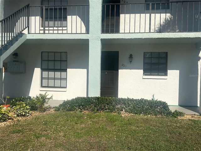 entrance to property with stucco siding and a yard