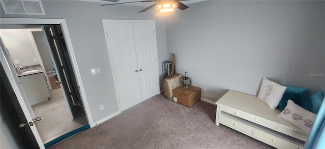 bedroom with visible vents, baseboards, ceiling fan, light colored carpet, and a closet