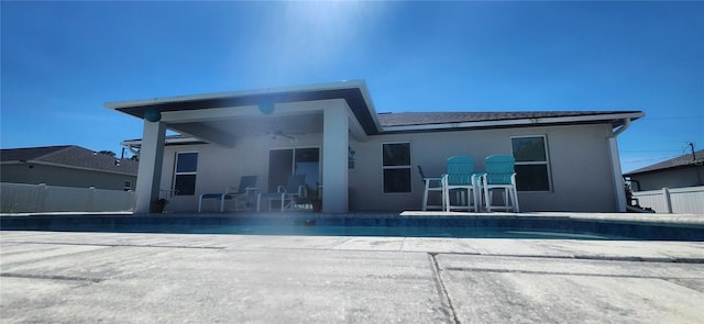 back of property featuring fence, a fenced in pool, ceiling fan, stucco siding, and a patio area