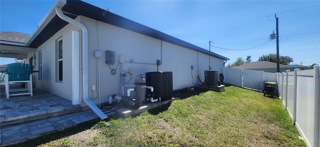 view of home's exterior with a lawn, a gate, a patio, a fenced backyard, and central AC unit